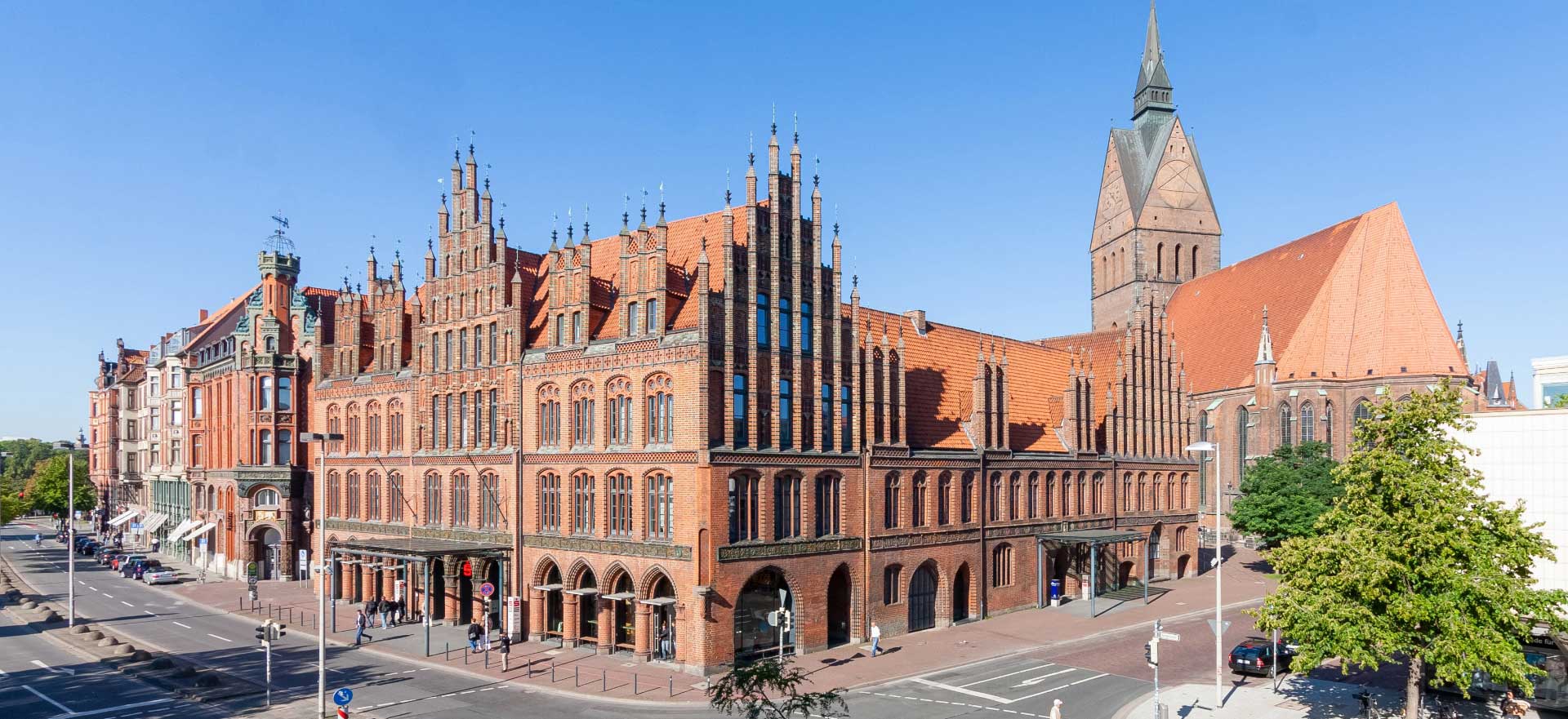 Historisches rotes Backsteingebäude des Alten Rathauses mit gotischer Architektur und Marktkirche im Hintergrund